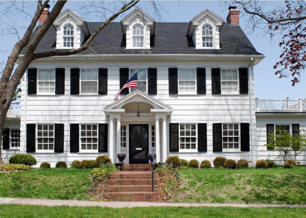 White colonial home with dark shutters.