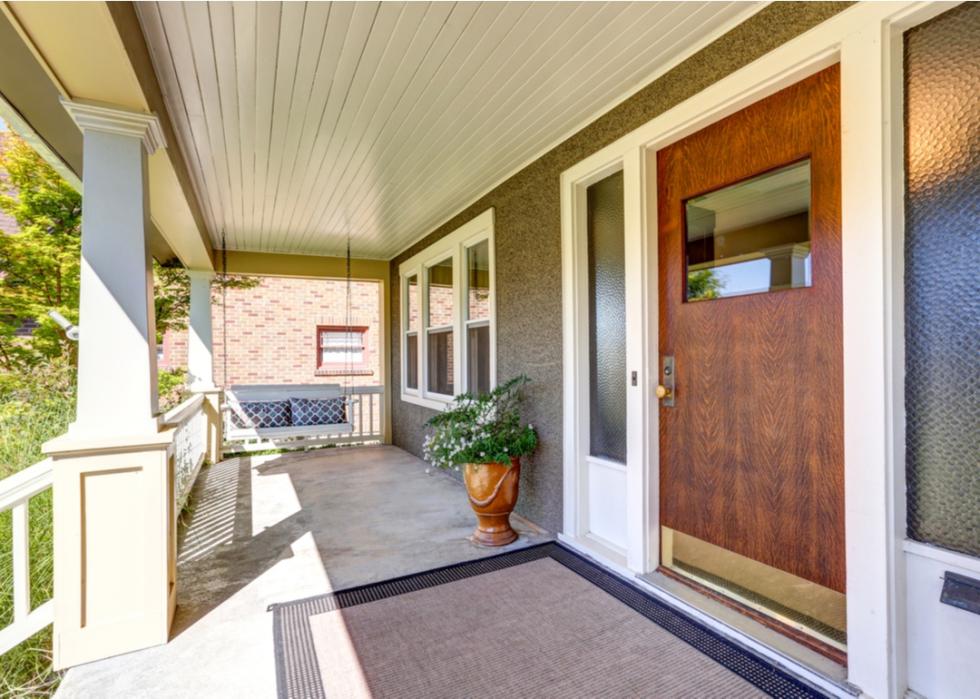 Big porch with wood door and a swing.