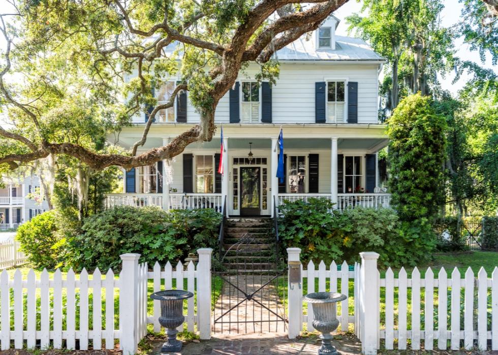 White colonial home surrounded by a white picket fence.