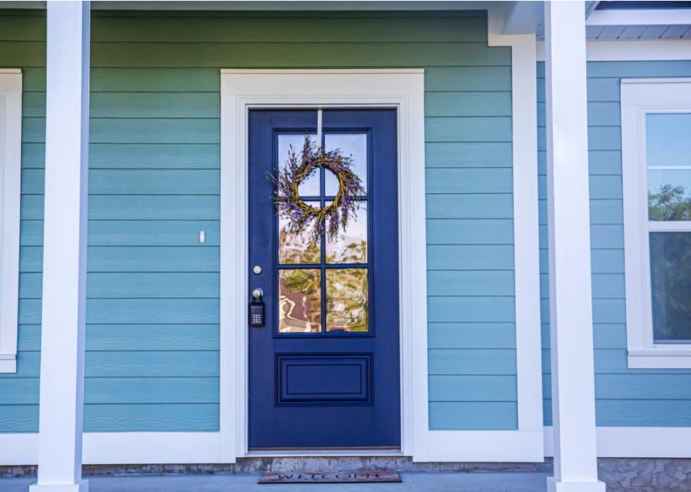 Blue craftsman home with a darker blue door covered in a wreath.