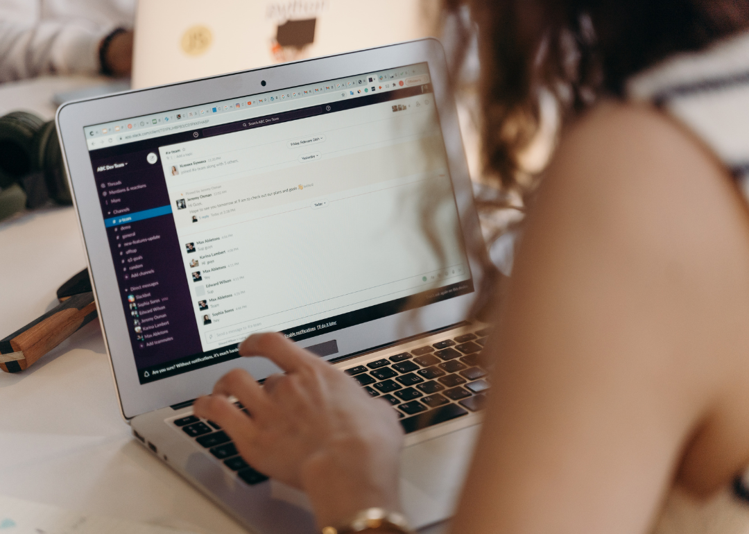 A young woman using Slack on a laptop.