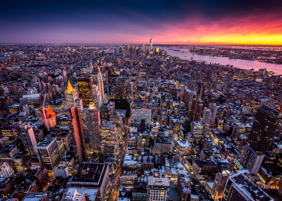 Lights glowing in aerial view of New York City downtown at sunset.