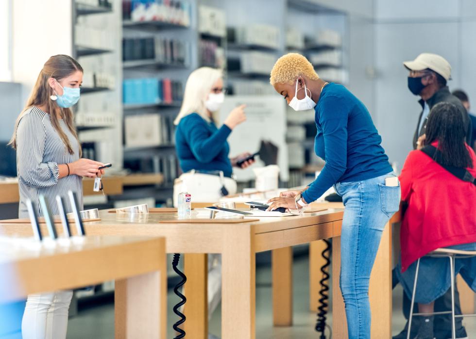 Employees wearing masks at an Apple store help customers.