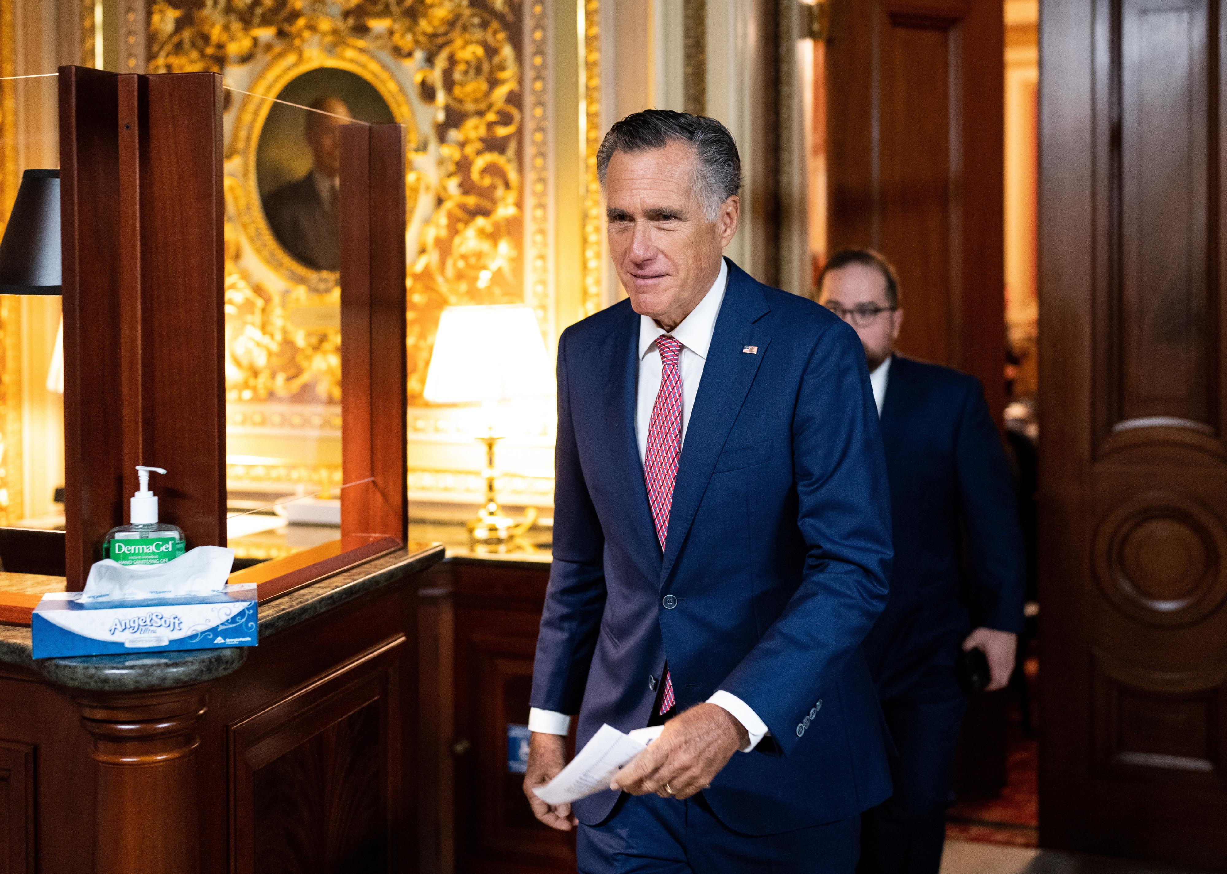 Mitt Romney in a blue suit walking through the U.S. Capitol.