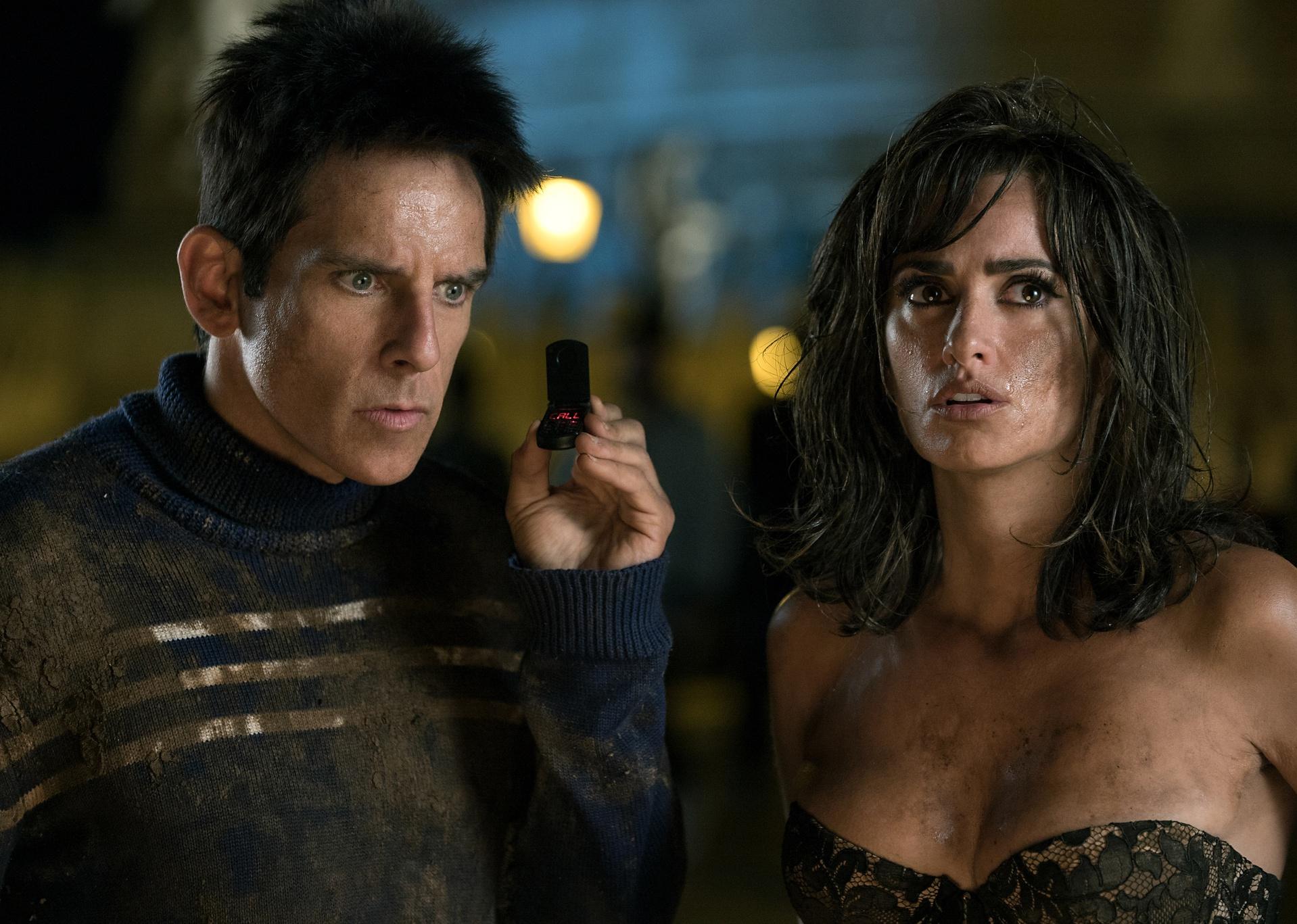 Ben Stiller listening to a tiny flip phoneand Penélope Cruz, both covered in dirt.