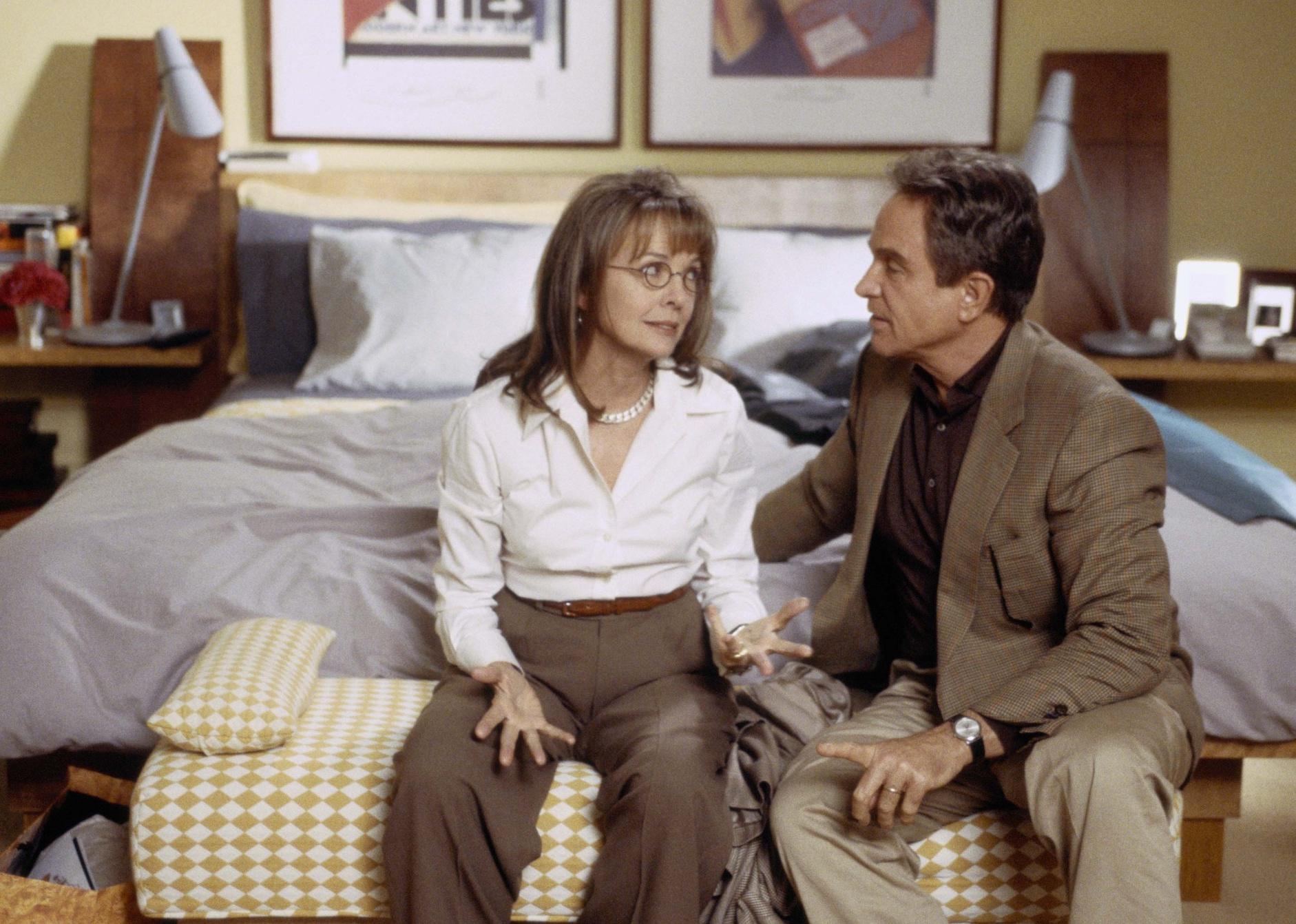 Diane Keaton and Warren Beatty sit at the foot of a bed talking.