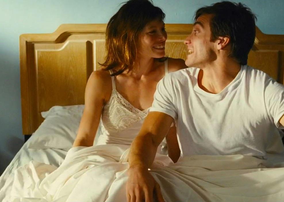 Jessica Biel and Jake Gyllenhaal laughing in bed together.