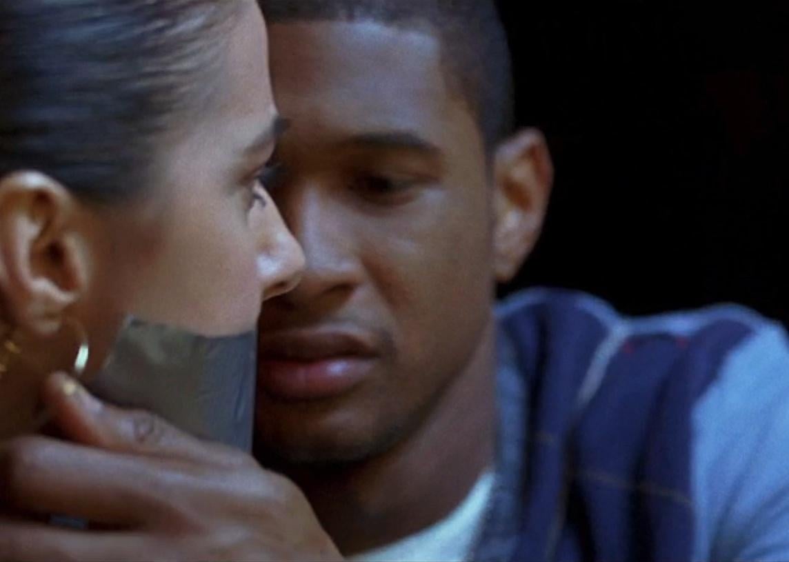 Usher taking tape off of a woman's mouth.