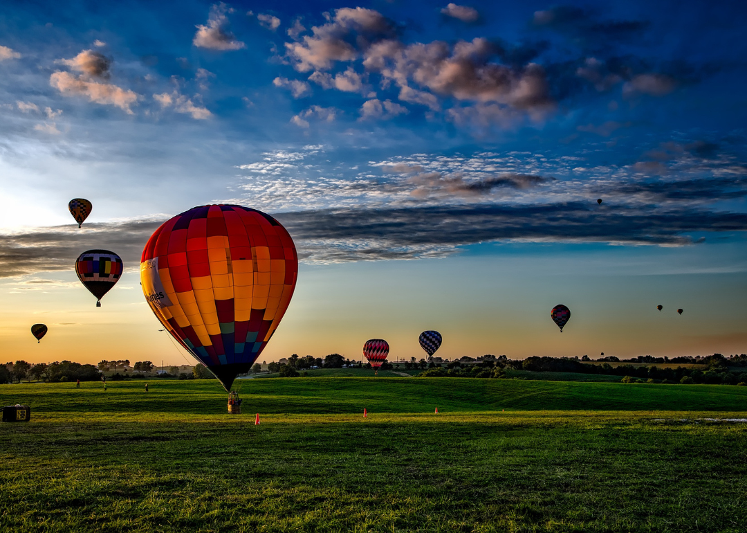 Colorful hot air balloons taking off and landing in a field.