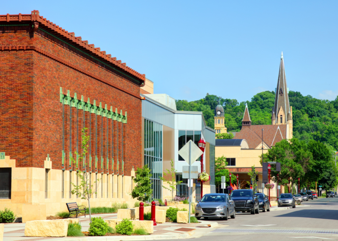 A large ornate brick building, a church and other small businesses on a street in Mankato.
