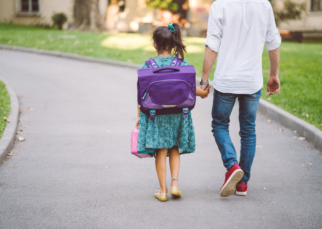 A dad walking his daughter to school.