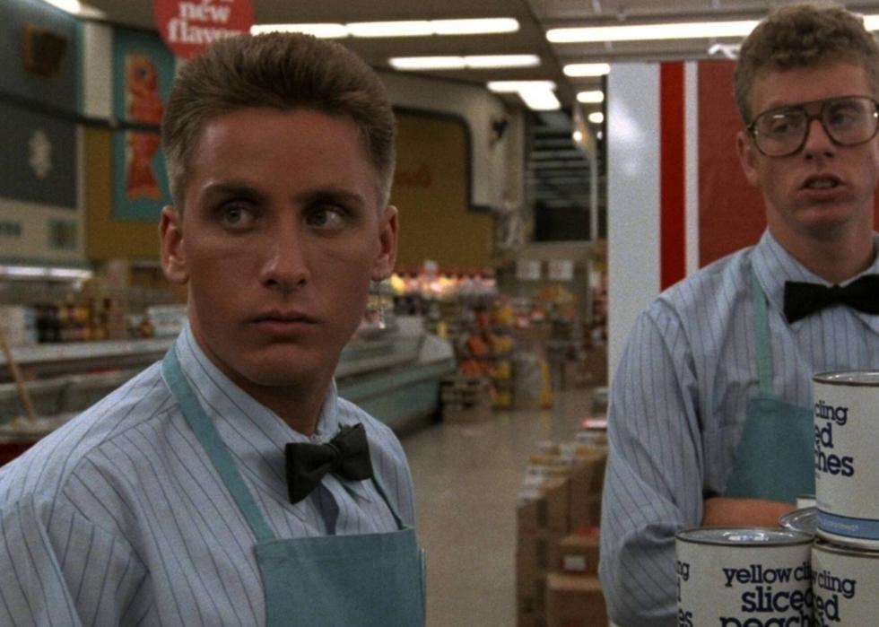 Two young boys in uniforms with bowties are working at a grocery market.