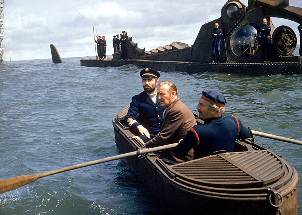 3 men on a small boat near a submarine.