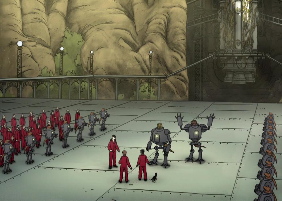 People in red suits and alien bots stand in a factory.