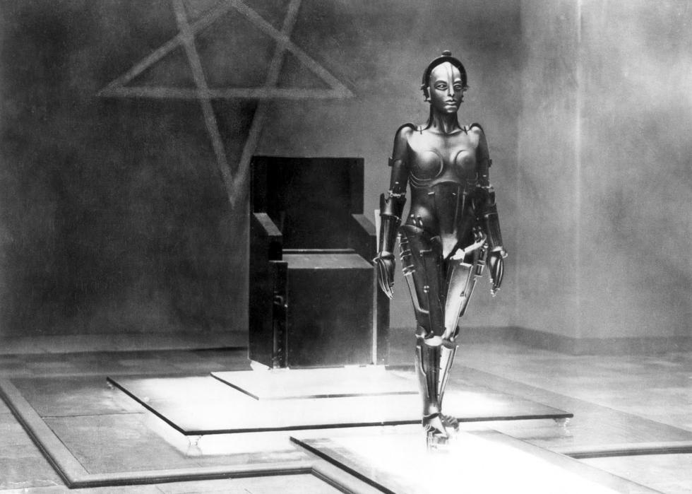 A female robot stands on a platform.