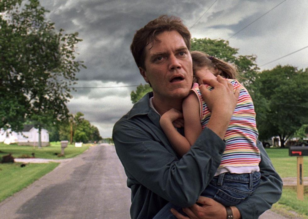 Man holding a little girl with ominous weather in the background.