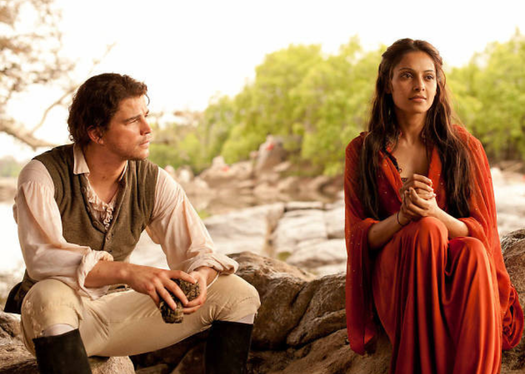 Josh Hartnett and Bipasha Basu dressed in different time periods sitting together.