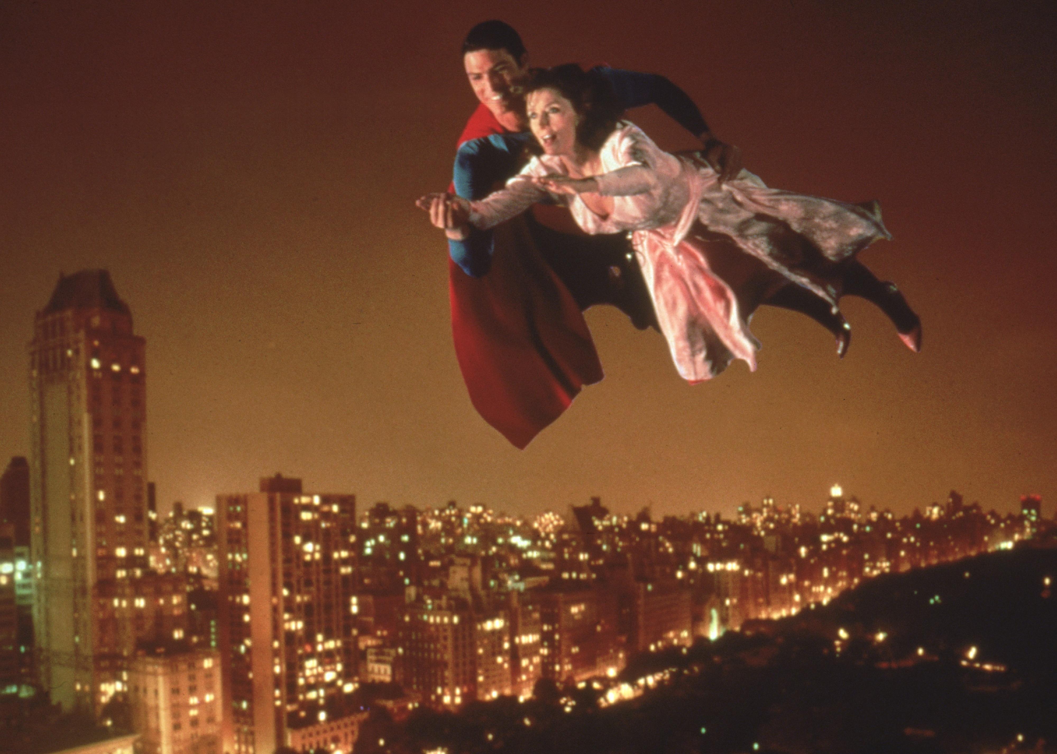 Christopher Reeve and Margot Kidder flying over a city at night.