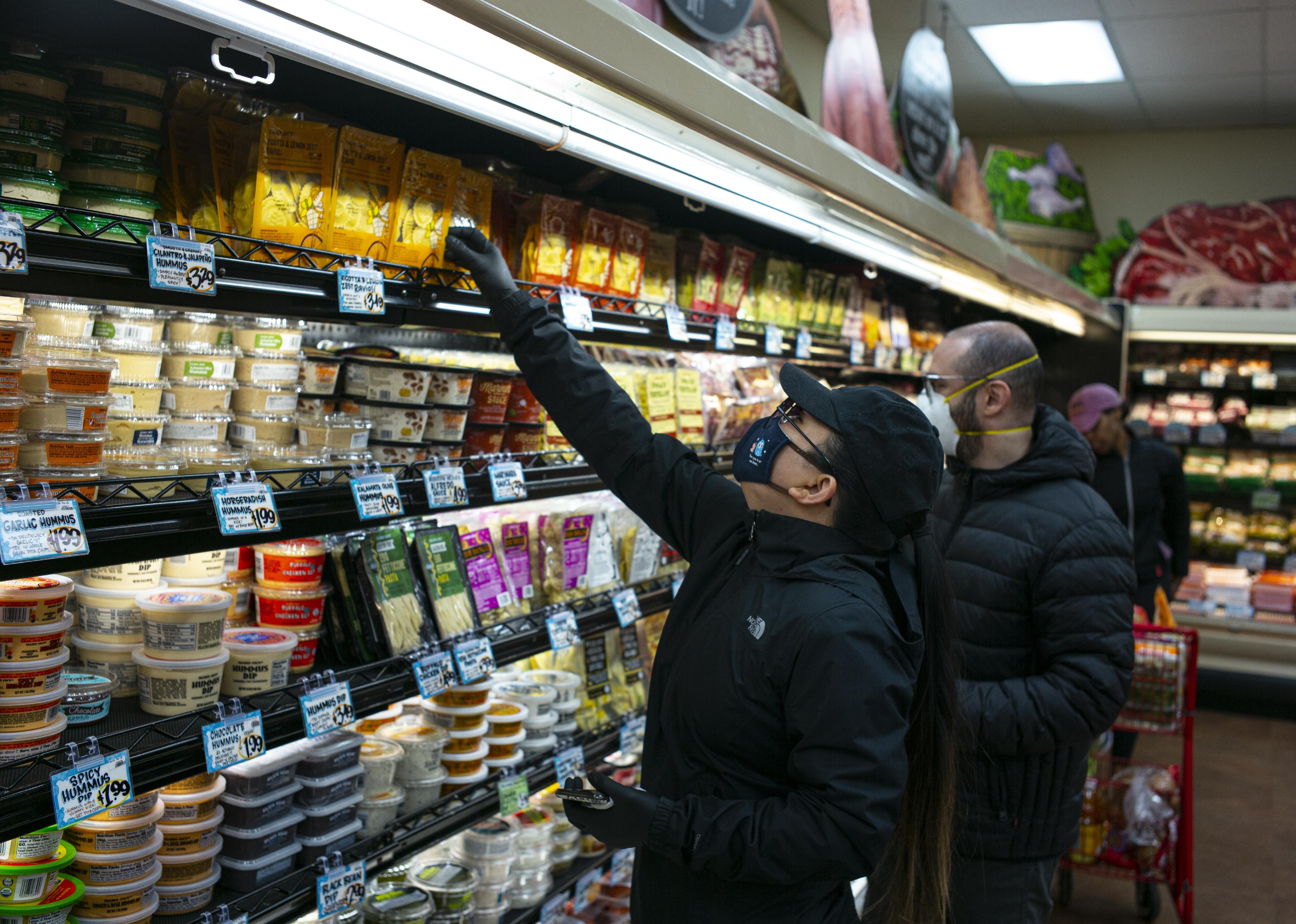 People wearing masks shop for groceries in the supermarket.
