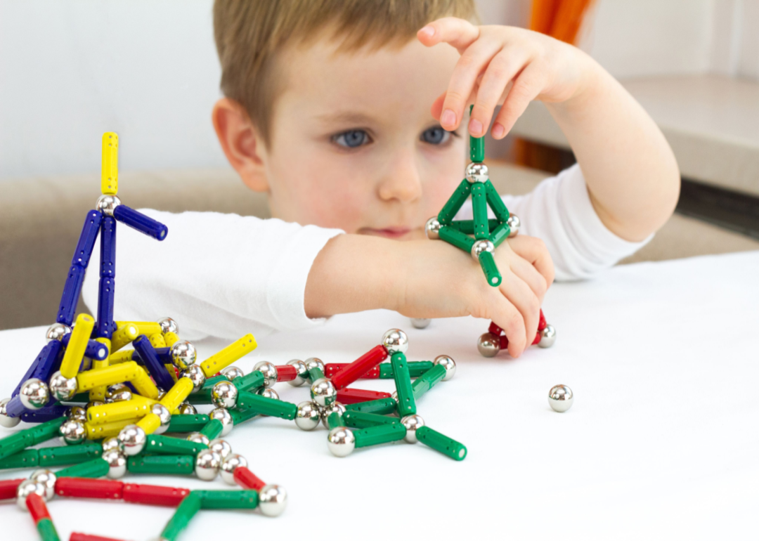 A young boy playing with colorful magnetic building toys.