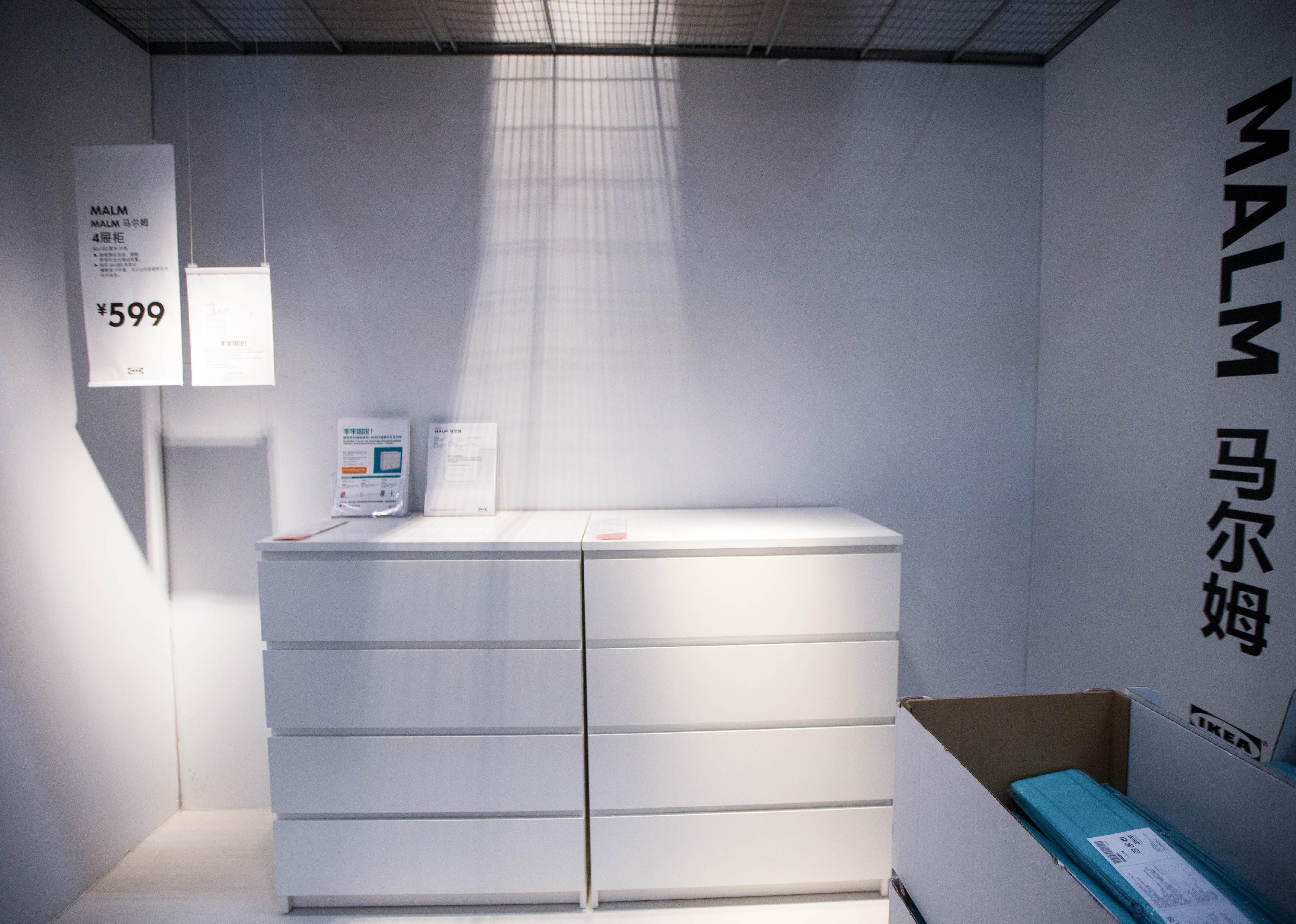 A white dresser without pulls in a white room at Ikea.