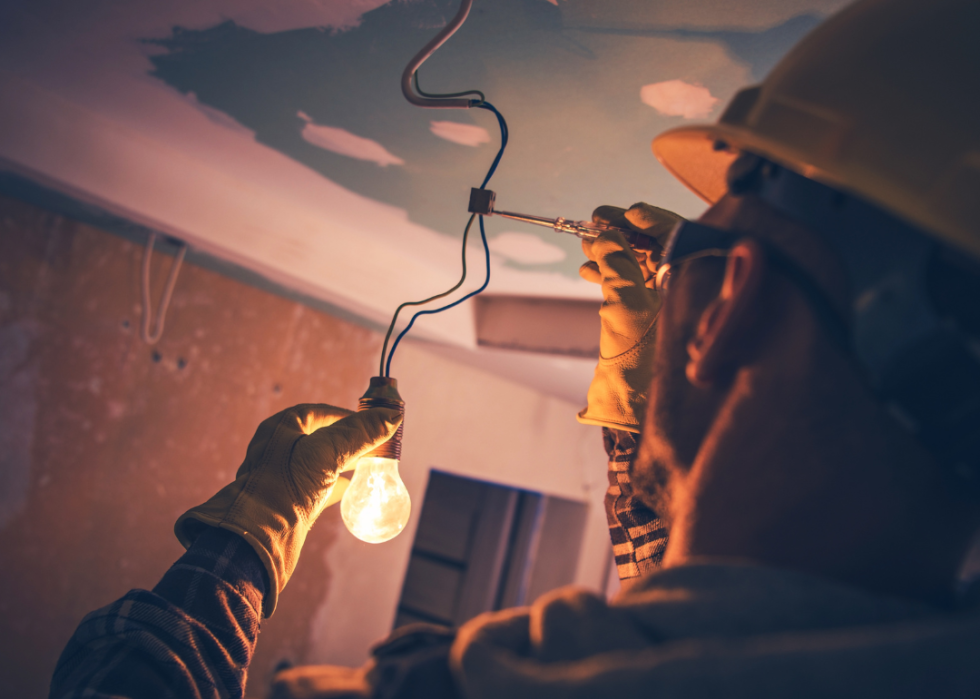An electrician working with wires and lights in the ceiling.