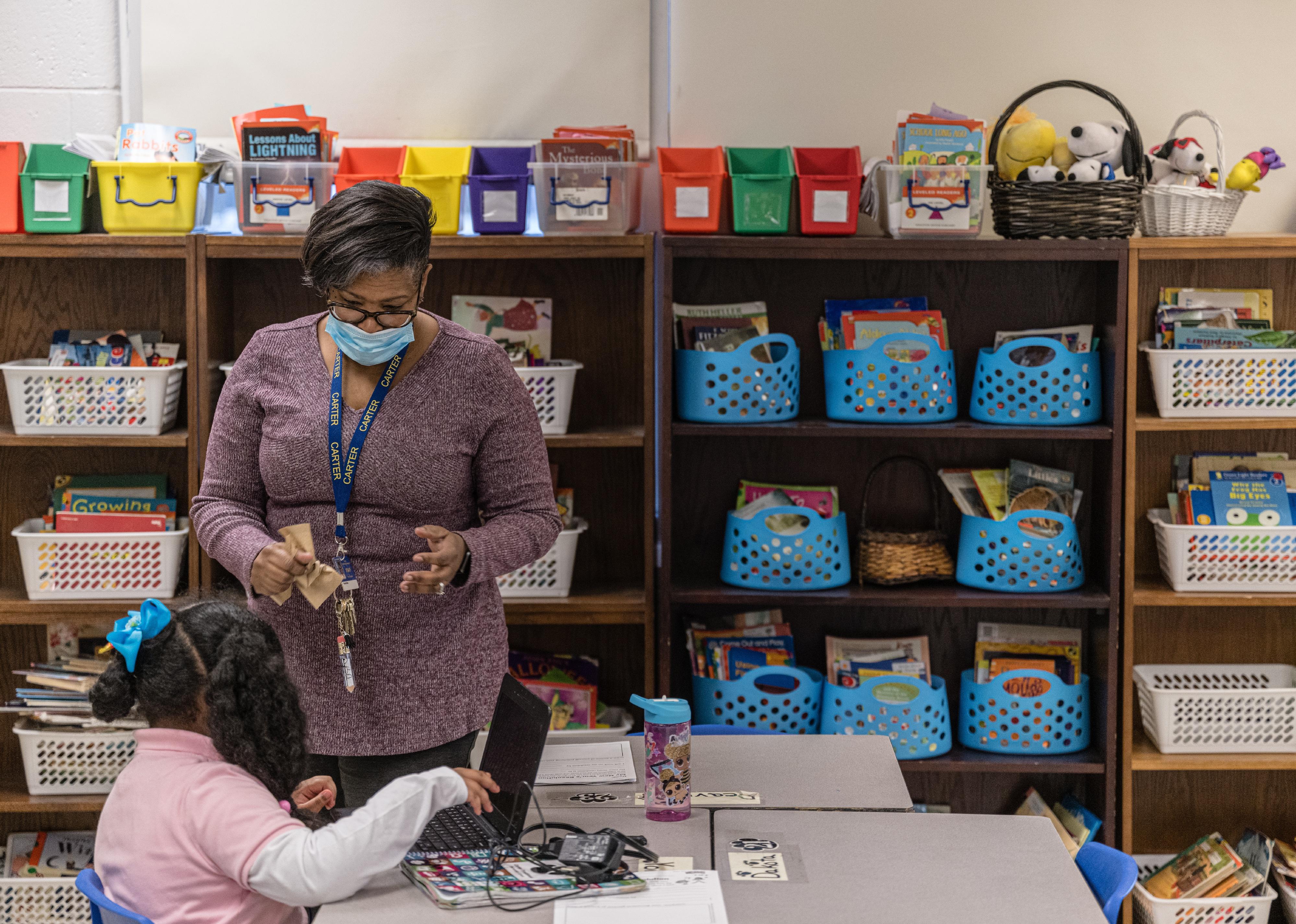 A young girl working with a teacher in a classroom.