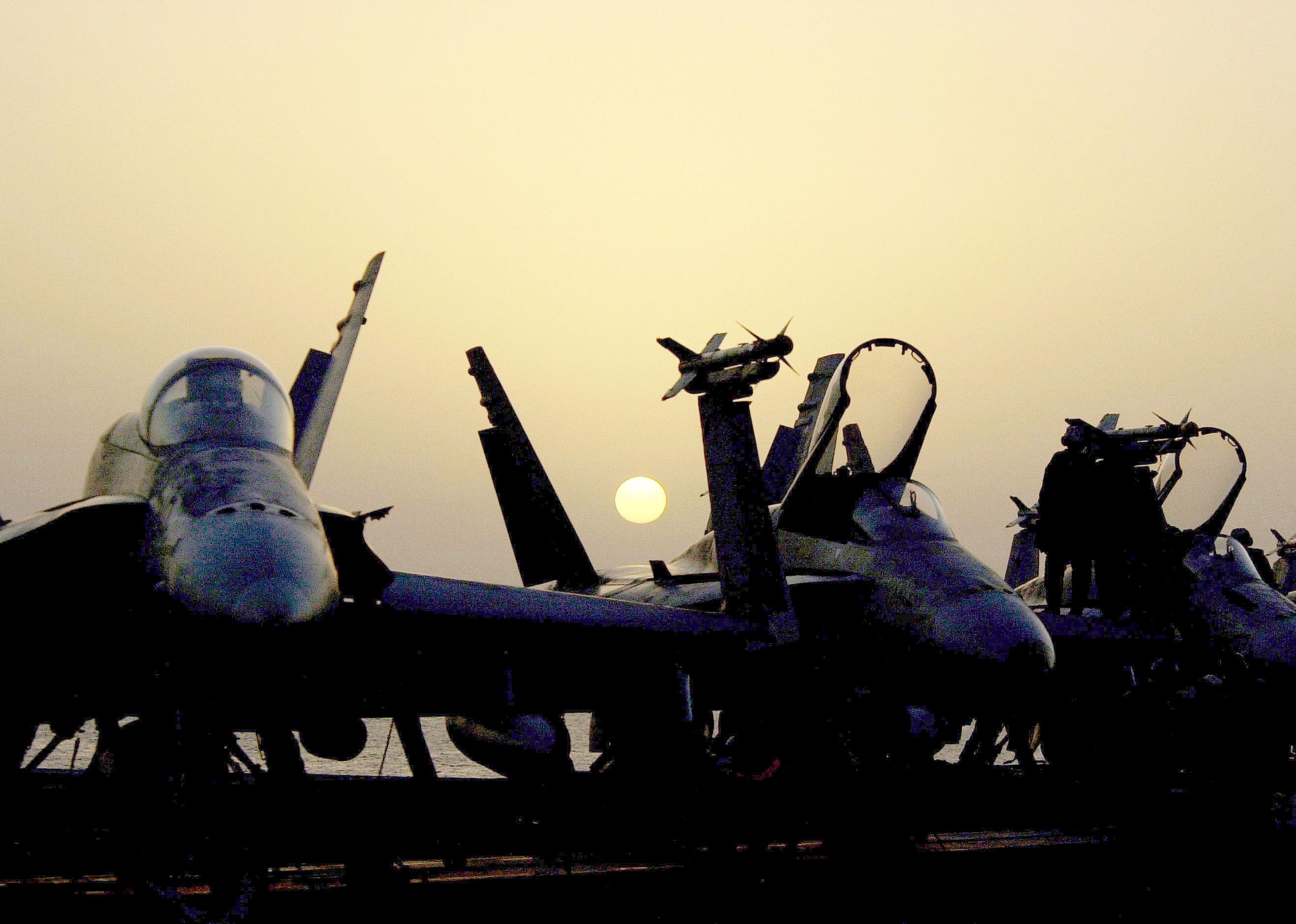 US Navy F/A-18 Hornet jets sitting on the flight deck waiting to be loaded.