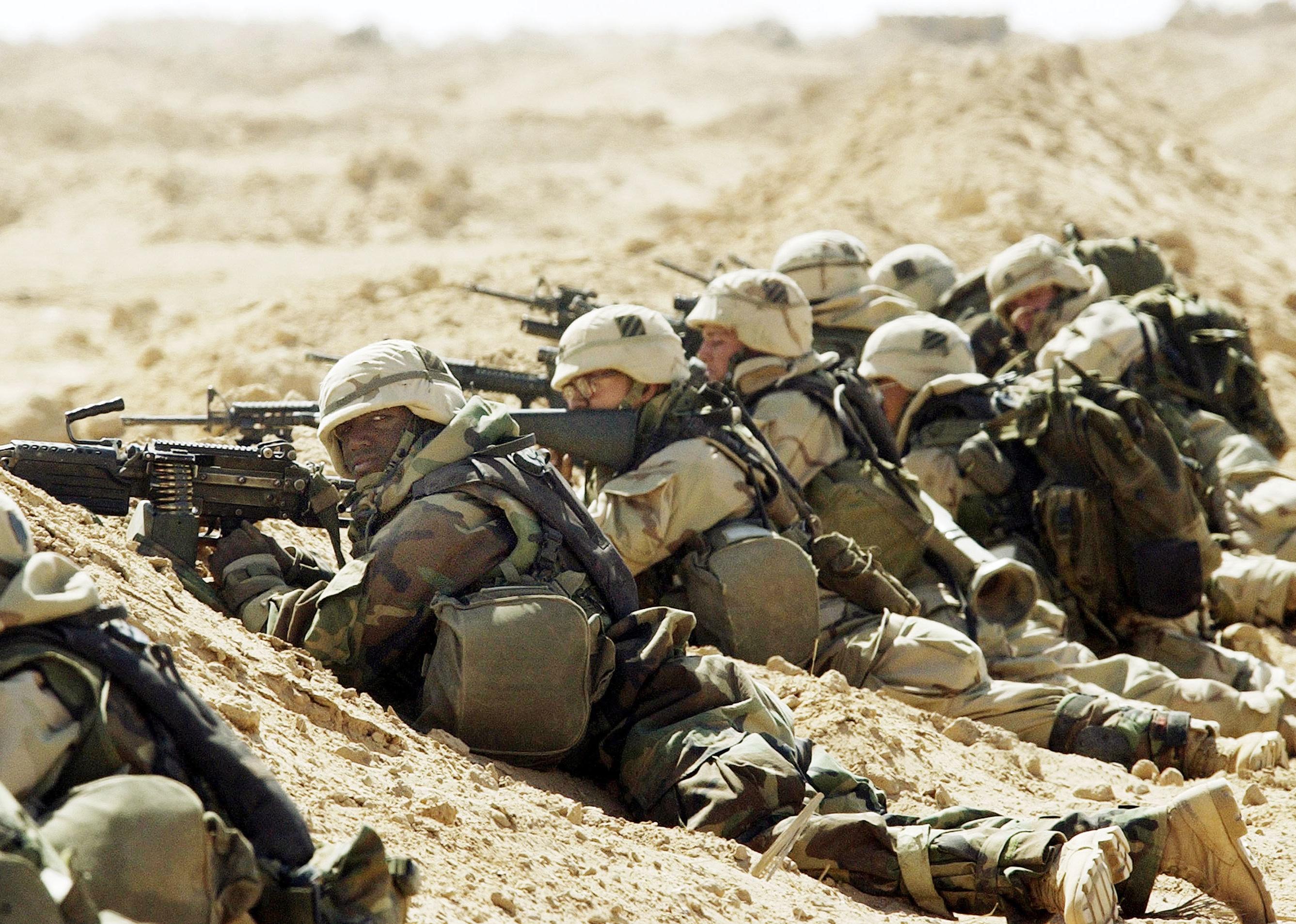 U.S. Army soldiers lined up on the ground in shooting position.