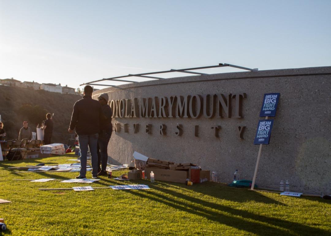 Students standing outside next to the Loyola Marymount sign.