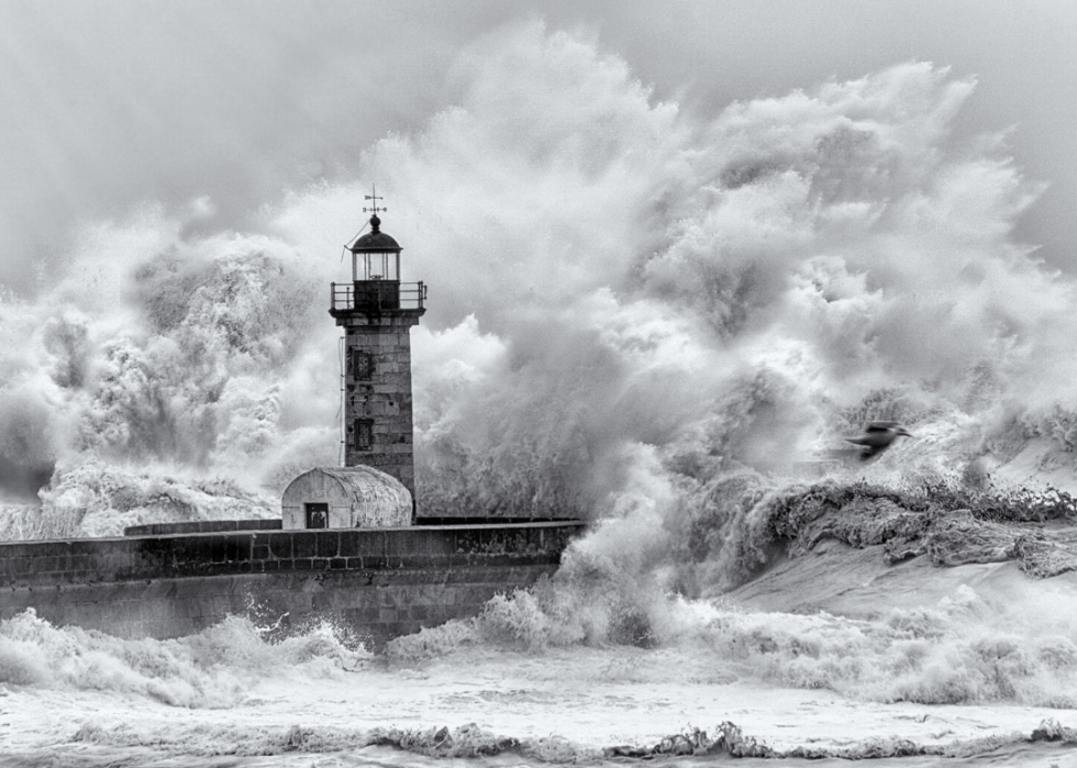 Massive waves crash against a lighthouse.