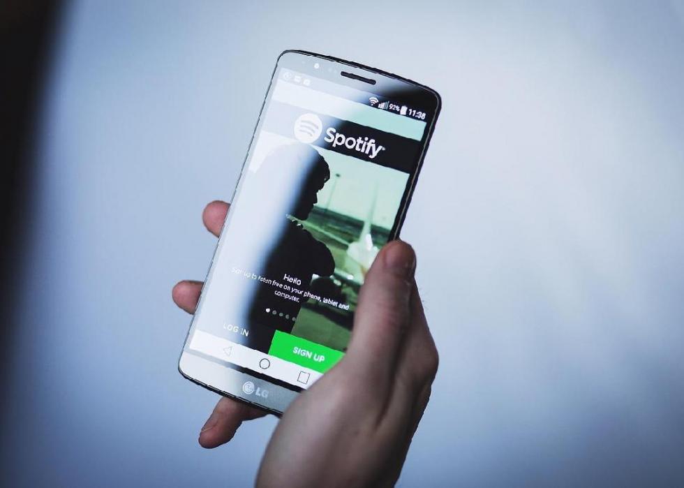 Person holding cellphone with Spotify app open.