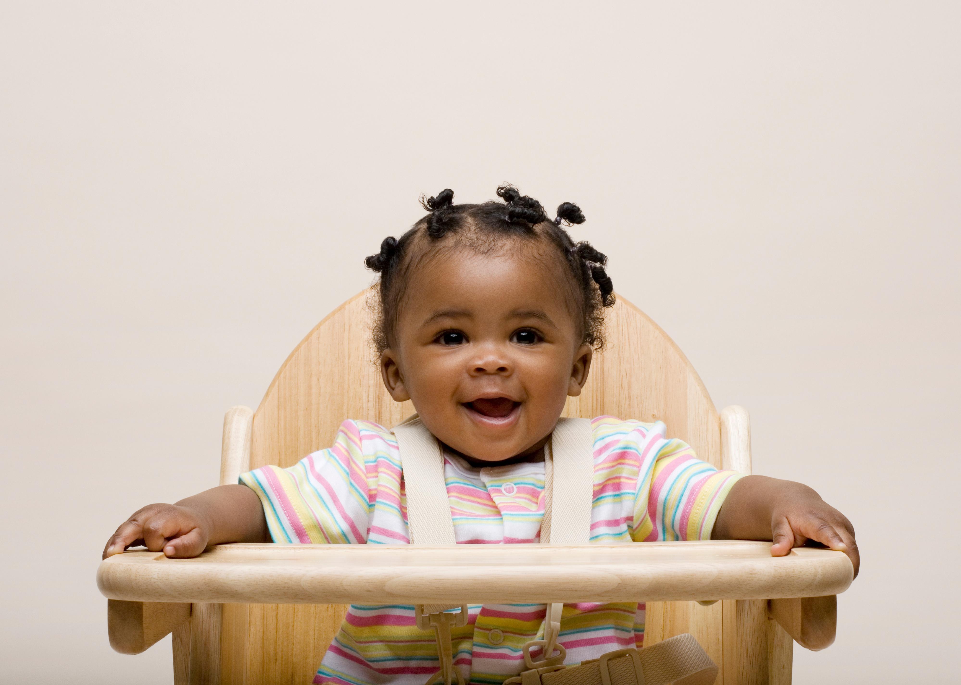 Baby girl in high chair smiling.