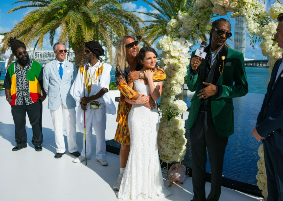Matthew McConaughey hugging Stefania LaVie Owen in a wedding dress, while standing next to Snoop Dogg, Jimmy Buffett, and Joshua Ritter, along with two other men, in The Beach Bum.