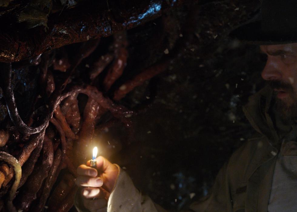 David Harbour holding a lighter to see what looks like tentacles everywhere.