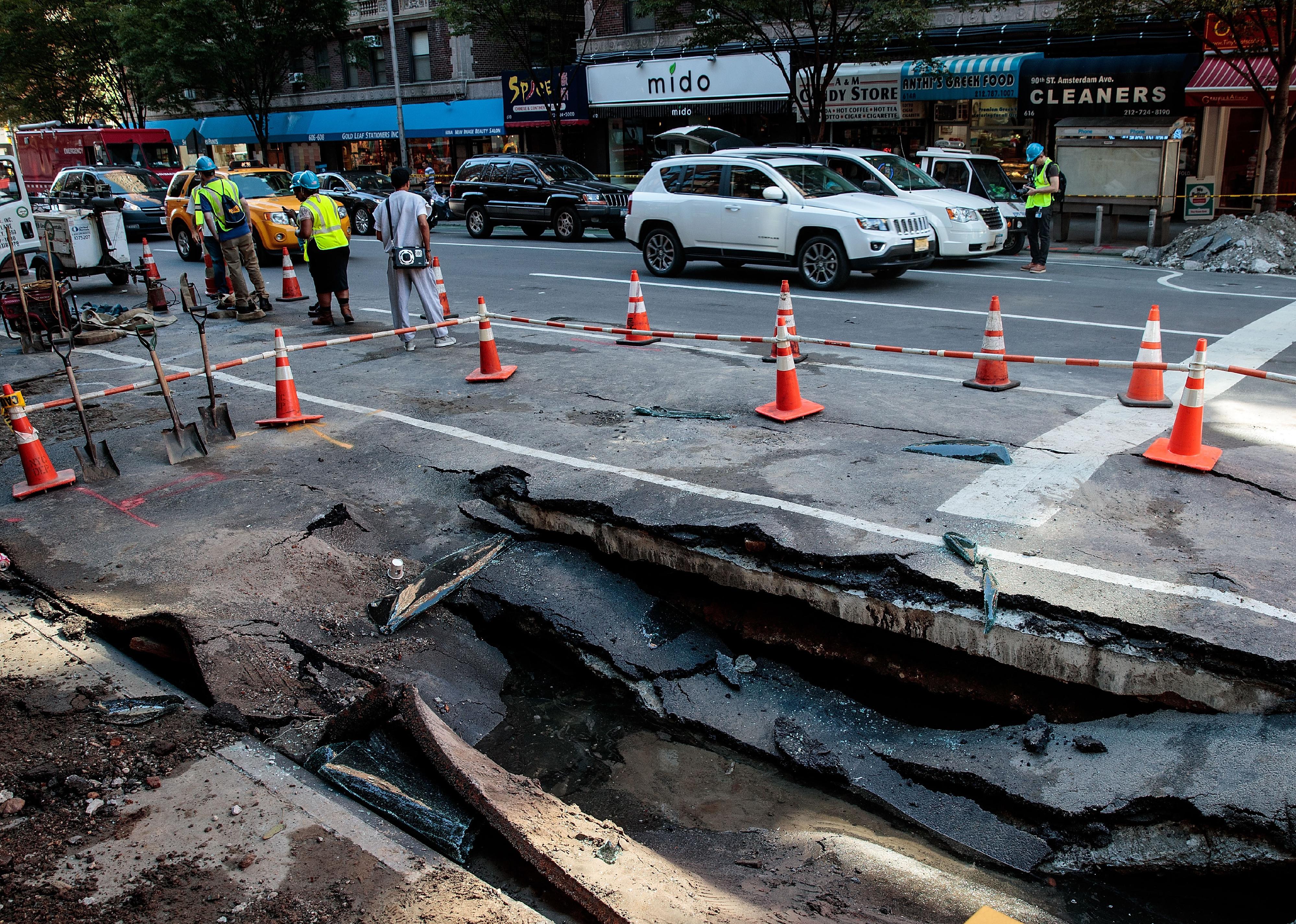 Traffic passes by a sinkhole caused by a water main break