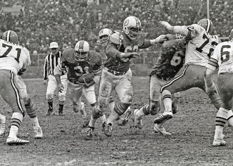 Running back Norm Bulaich #31 of the Miami Dolphins runs behind the blocking of center Jim Langer #62 and guard Bob Kuechenberg #67 as defensive linemen Walter Johnson #71 and Jerry Sherk #72 and linebacker Bob Babich #60 of the Cleveland Browns pursue the play as snow falls during a game at Cleveland Municipal Stadium on November 28, 1976 in Cleveland, Ohio. The Browns defeated the Dolphins 17-13. (Photo by George Gojkovich/Getty Images)