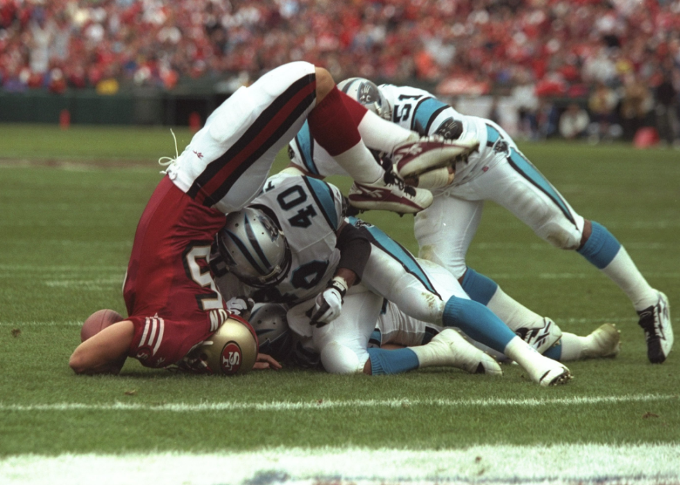Tight end Ted Popson of the San Francisco 49ers (left) gets tackled by Carolina Panthers linebacker Sam Mills (#51) and safety Pat Terrell, 1996.