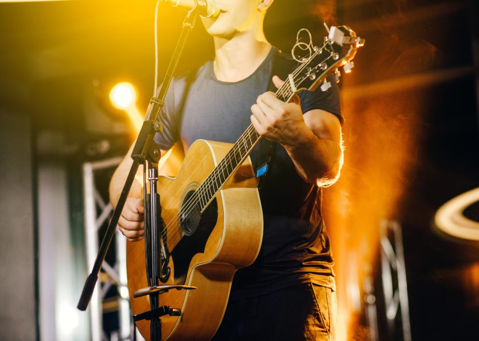 Onstage singer plays an acoustic guitar