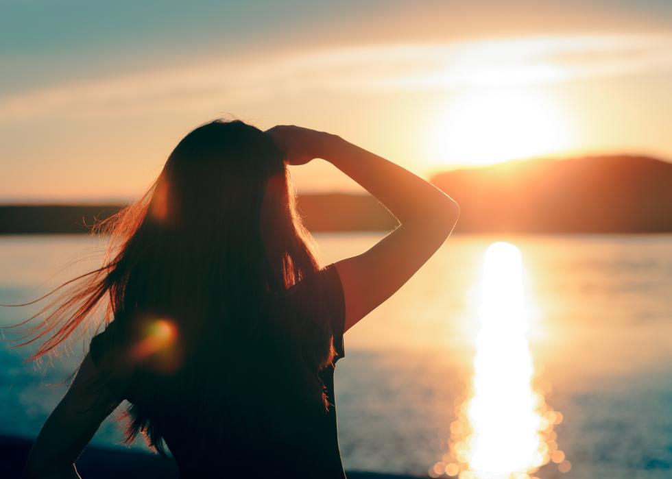 Woman looking at the sunset by the sea.