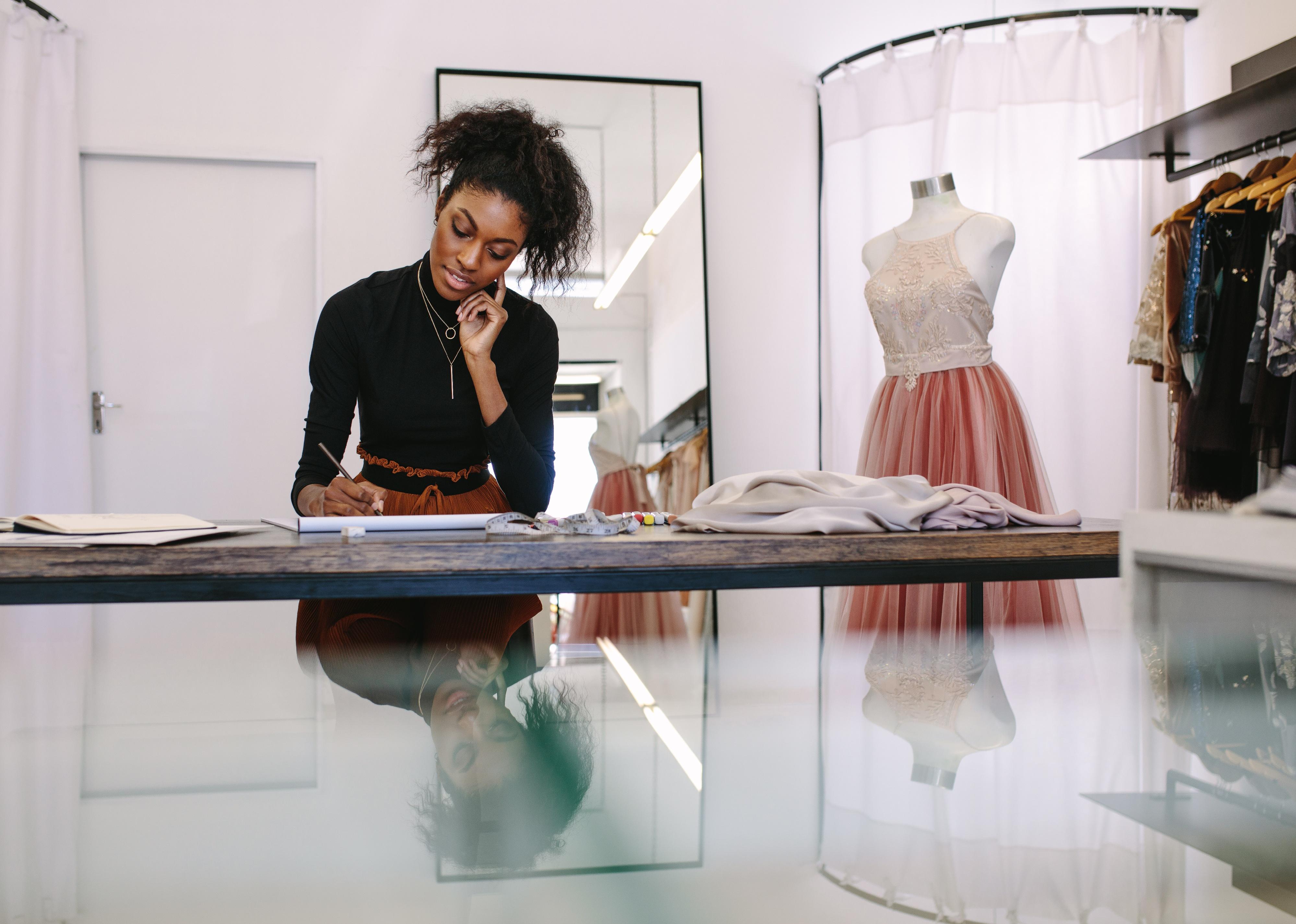 Fashion designer sketching a design sitting at a table.