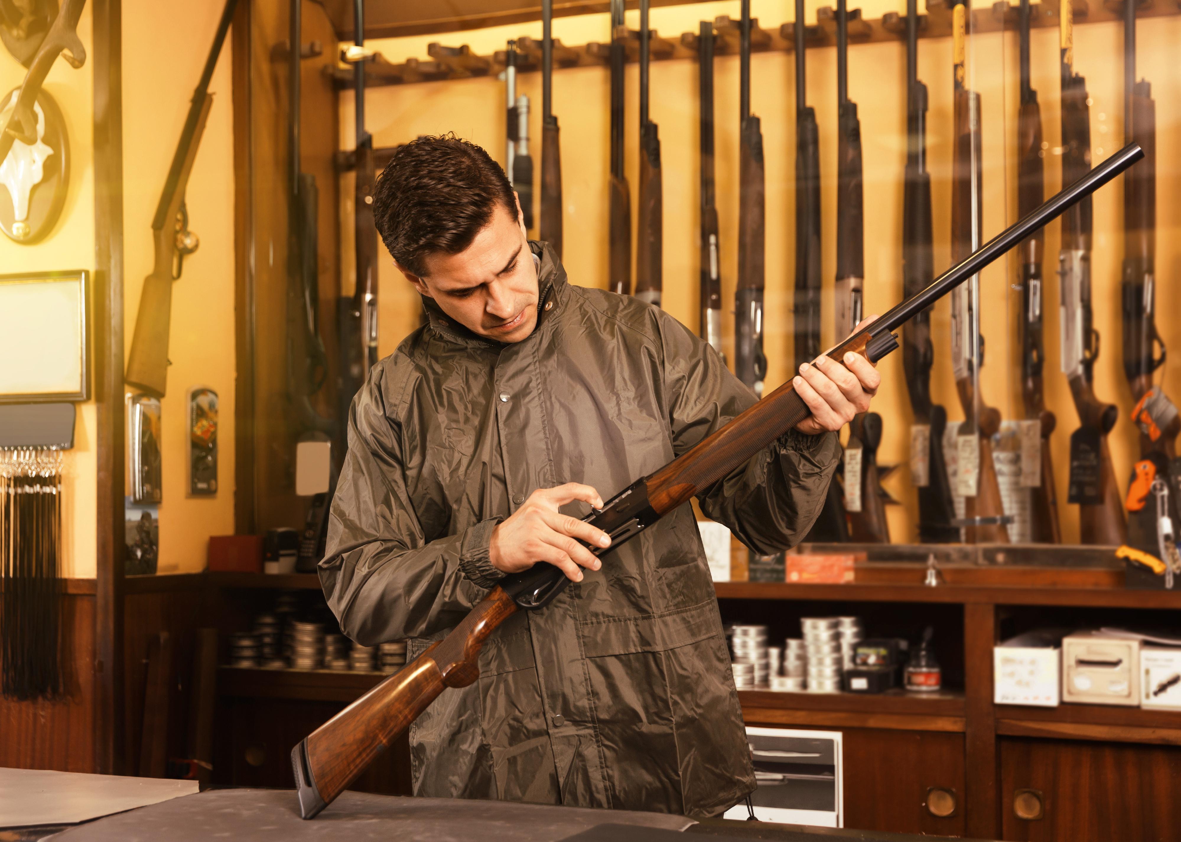 Portrait of person in gun shop showing rifle.