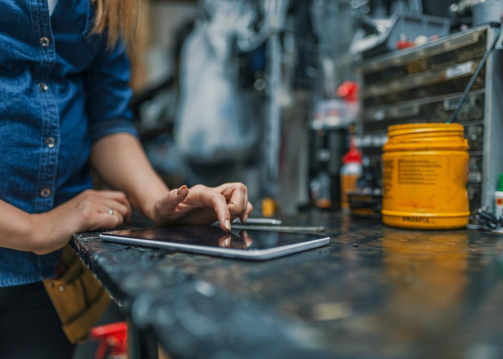 Female bicycle repair technician using digital tablet in bicycle shop