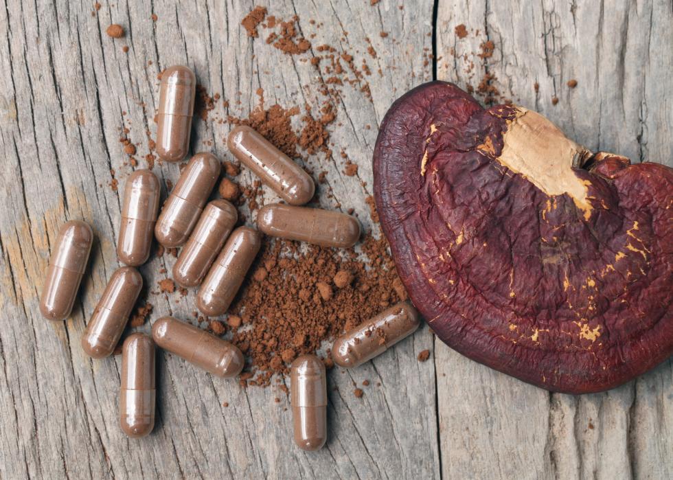 Mushroom and pills on wooden background.