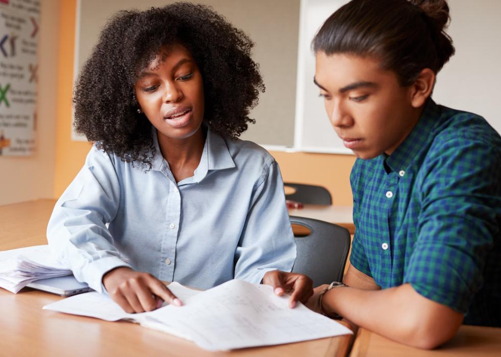 A tutor points to papers in front of her and a teen student she is working with.