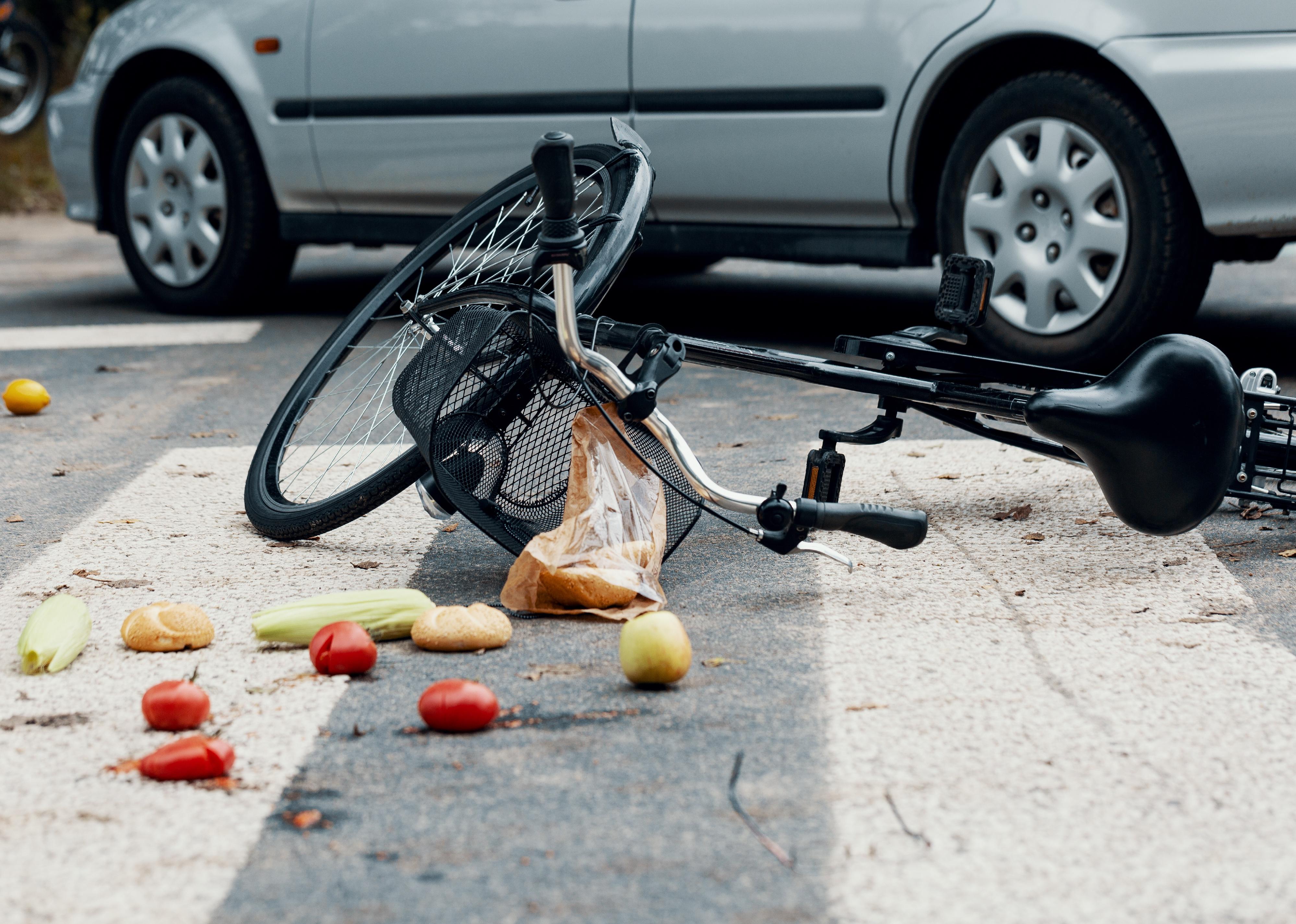 Groceries and broken bike on pedestrian crossing after collision with a car.