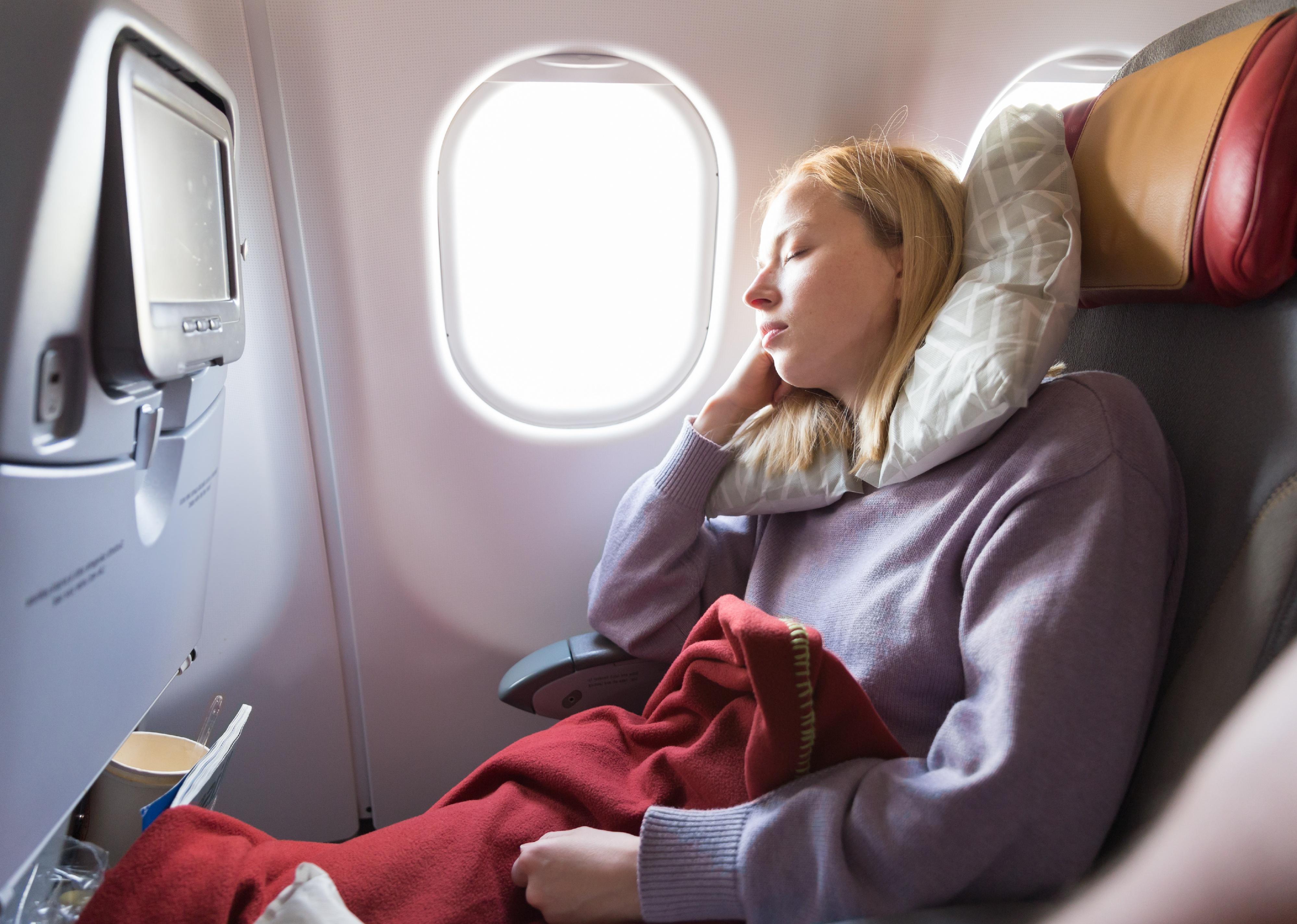 Woman sleeping while traveling by airplane on long distance flight.
