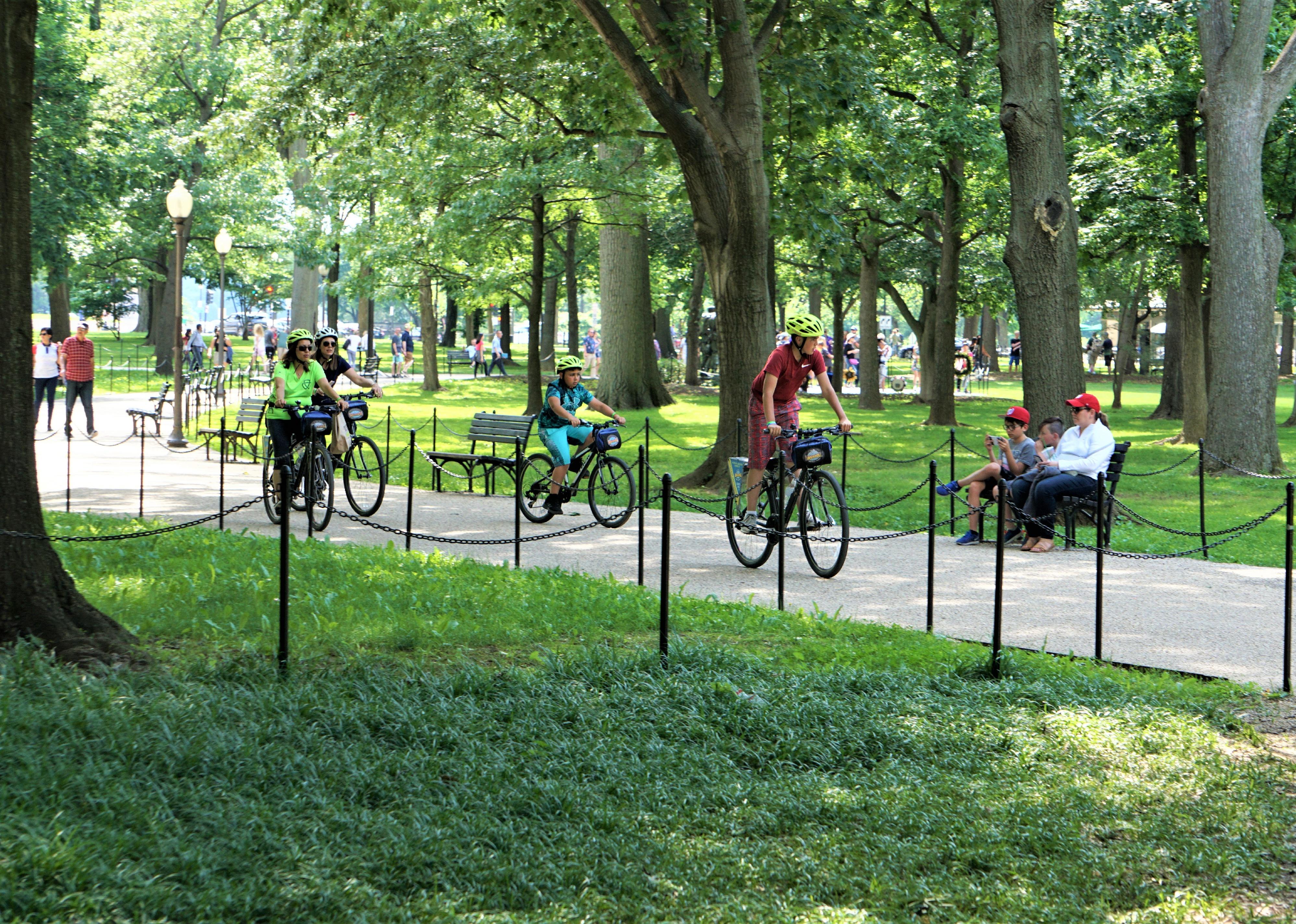 A group of tourists riding the bicycles on the pathway in the park of National Mall in D.C.