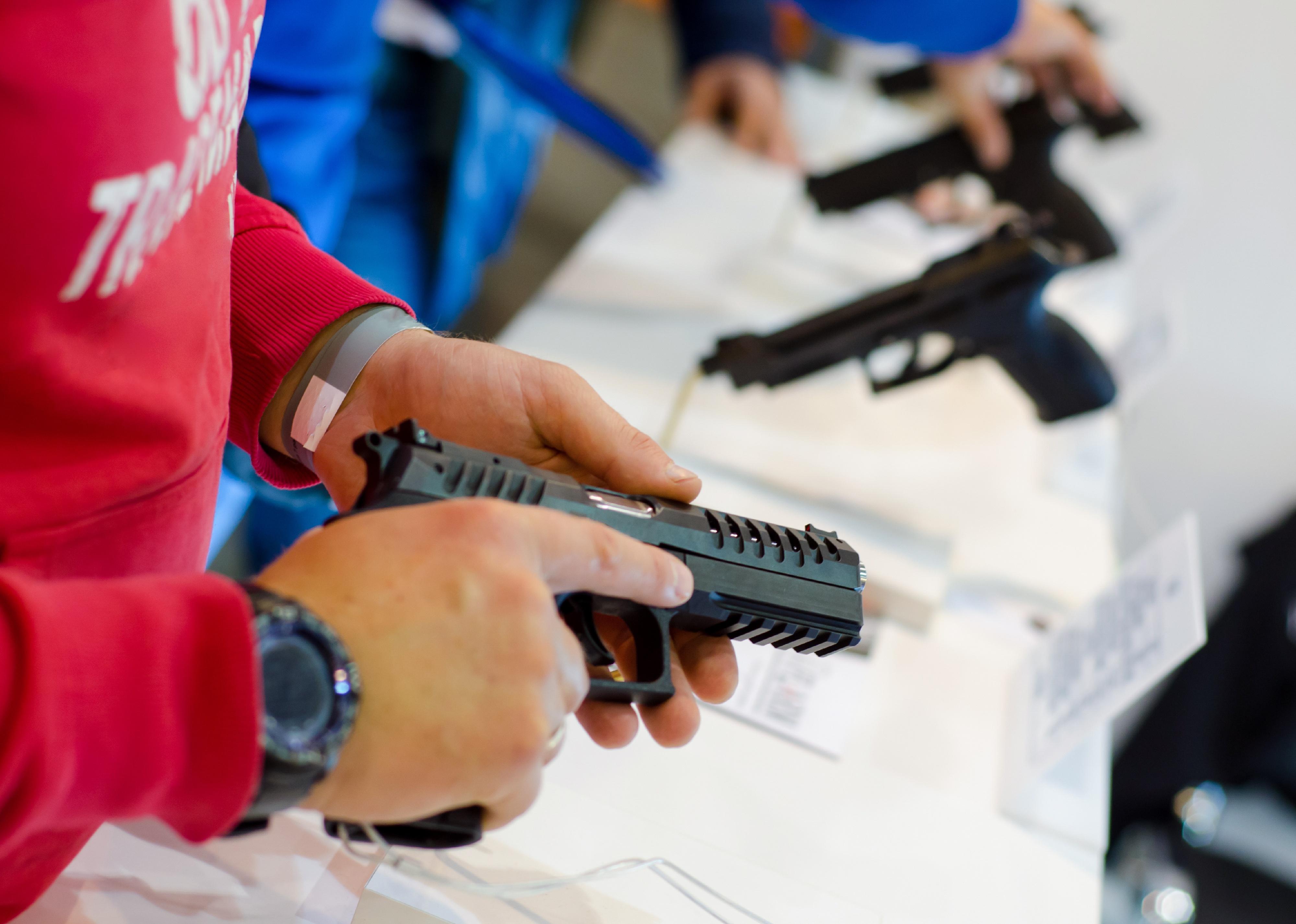 Close up of a person holding a gun in a store.