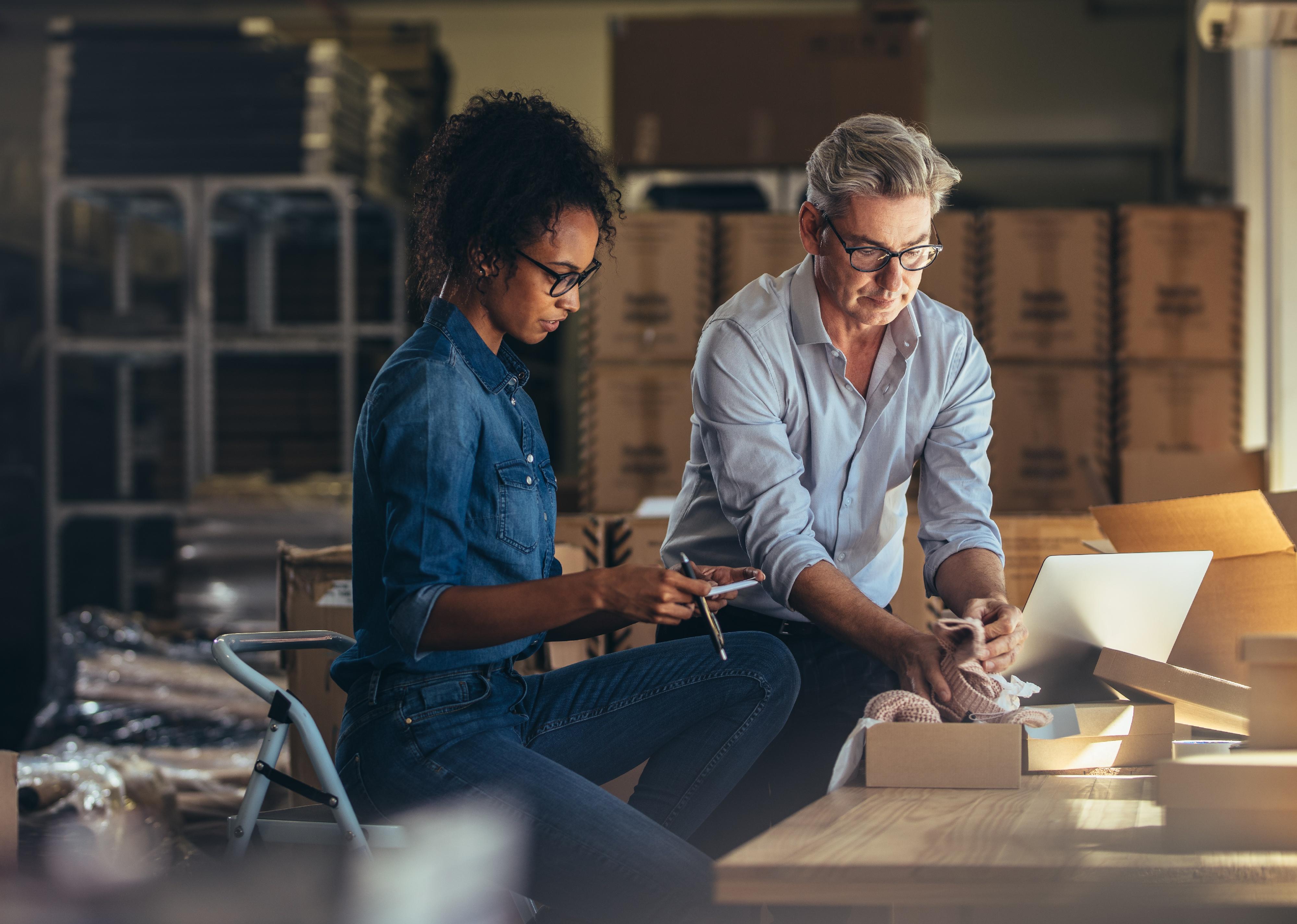 Two people in warehouse packing a shipment.